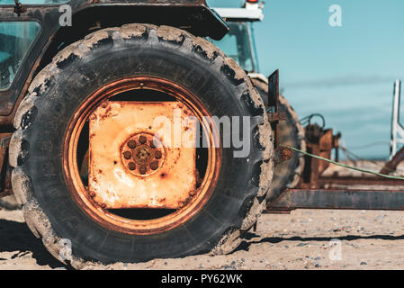 Un vieux rusty la roue du tracteur sur la plage Banque D'Images