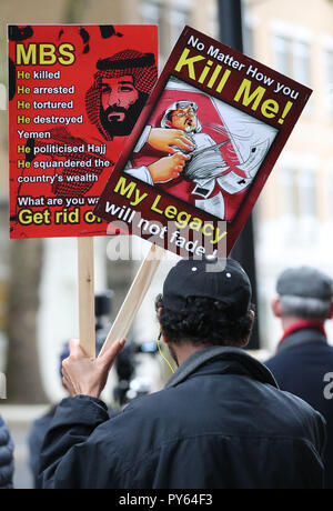 Un homme détient des affiches dénonçant l'Arabie Prince Mohammed bin Salman et saluant le journaliste Jamal Khashoggi tués lors d'une manifestation devant l'ambassade d'Arabie saoudite, au centre de Londres. Banque D'Images