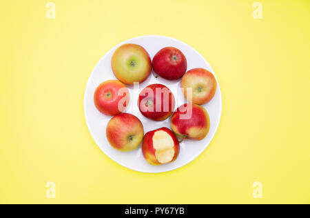 Plusieurs ensemble de pommes rouges et d'un piqué dans une assiette sur un fond jaune de l'automne composition et concept. Banque D'Images