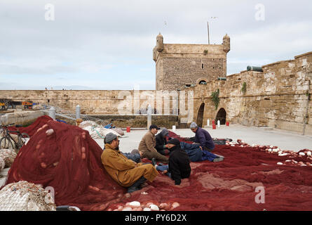 Les hommes de la réparation des filets de pêche dans le port de pêche d'Essaouira, Maroc. Banque D'Images