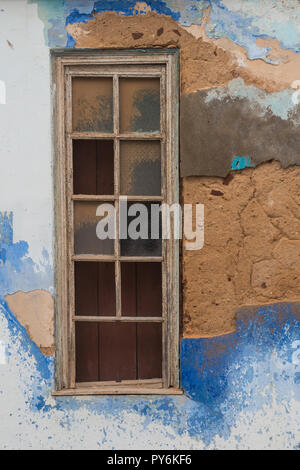 Mur d'une maison abandonnée à la façade blanche et plusieurs tonalités de couleur bleue, de nombreux trous sans façade. La fenêtre de temps en partie avec du verre brisé. Silves, Banque D'Images