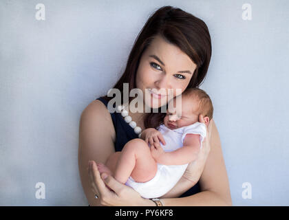 Mother holding newborn baby face à l'appareil photo smiling