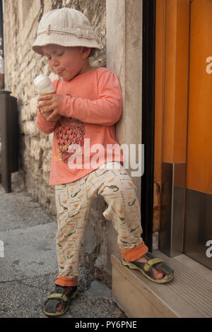 White baby girl licking manger une glace sur une chaude journée ensoleillée en Croatie en vacances. Banque D'Images