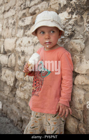 White baby girl licking manger une glace sur une chaude journée ensoleillée en Croatie en vacances. Banque D'Images