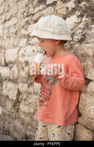 White baby girl licking manger une glace sur une chaude journée ensoleillée en Croatie en vacances. Banque D'Images