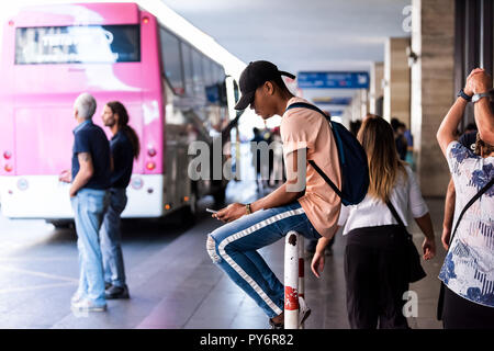 Rome, Italie - le 4 septembre 2018 : Jeune homme assis avec téléphone en entrée de la gare ferroviaire de Termini, jour d'été, les touristes les gens marcher waitin embarquement Banque D'Images