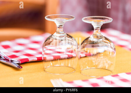 Gros plan macro de deux verres à l'envers sur verre table de restaurant à Rome, Italie, l'italien à l'extérieur dans un style traditionnel café de la rue de la chec rouge et blanc Banque D'Images