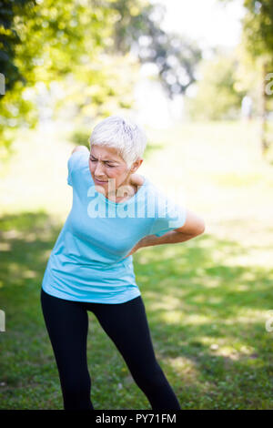 Remise en forme Senior woman rubbing les muscles du bas de son dos. Les maux de dos Banque D'Images