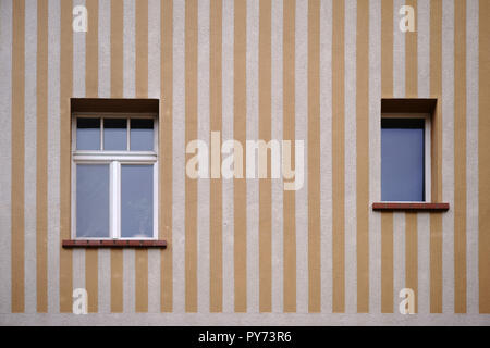 Le mur de la maison avec un carton jaune à rayures beige et peinture murale avec deux fenêtres. Banque D'Images
