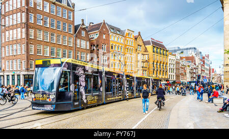 Les touristes et un tramway à l'occupé et célèbre place du Dam, dans le centre-ville historique d'Amsterdam aux Pays-Bas Banque D'Images