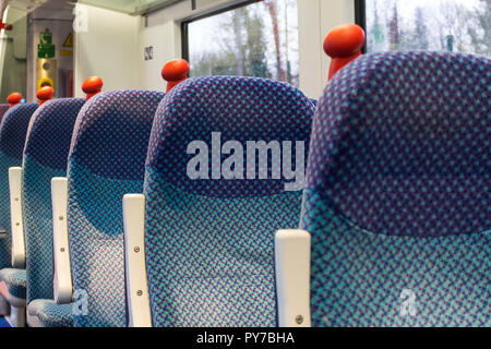 Rangée de sièges vides sur un train avec poignées rouges. NI LES CHEMINS DE FER, Translink, Belfast, N.Ireland. Banque D'Images