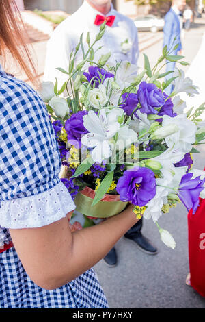 Close-up of groom's hand holding bride's wirst tendre, nature, soleil, détails, vert Banque D'Images