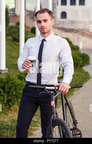 Jeune homme d'affaires avec le vélo de boire du café tasse à emporter Banque D'Images