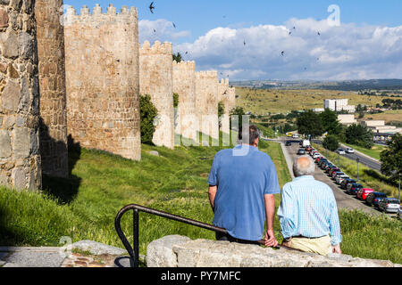 Avila, Espagne - 2 juillet 2018 : deux hommes assis sur la scène d'arpentage ferroviaire avec les oiseaux au-dessus. La ville est un site du patrimoine mondial. Banque D'Images