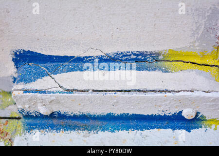 Le vieux mur est peint avec peinture blanche et le fragment sélectionné est peint avec de la peinture jaune et bleu Banque D'Images