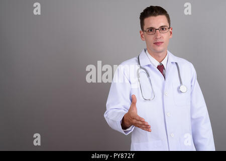 Jeune homme séduisant médecin poignée donnant et looking at camera Banque D'Images