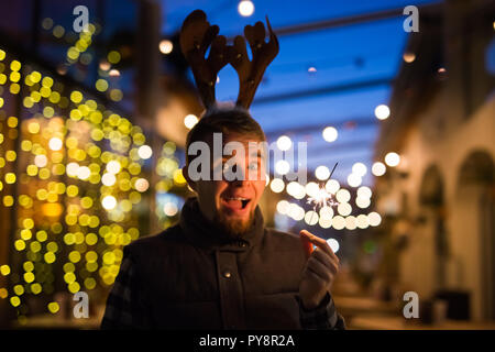 Les gens, les vacances de Noël - concept et surpris l'homme dans les cornes de cerf tenant deux baguettes à la lumière ou à l'extérieur des bengals Banque D'Images