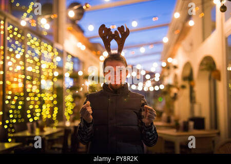 Les gens, les vacances de Noël - concept et surpris l'homme dans les cornes de cerf tenant deux baguettes à la lumière ou à l'extérieur des bengals Banque D'Images