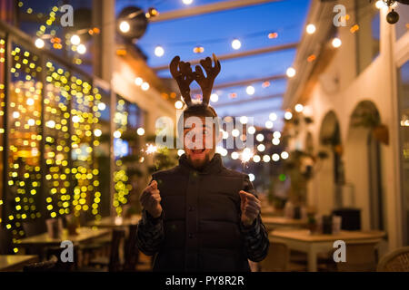 Les gens, les vacances de Noël - concept et surpris l'homme dans les cornes de cerf tenant deux baguettes à la lumière ou à l'extérieur des bengals Banque D'Images