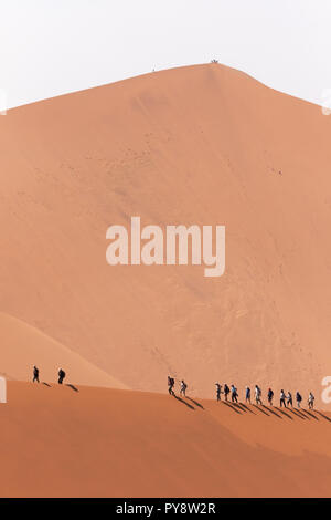 Les touristes à marcher le long de la crête d'une dune de sable ; Big Daddy en arrière-plan ; Dune Sossusvlei, Désert du Namib, Namibie, Afrique du Sud Banque D'Images