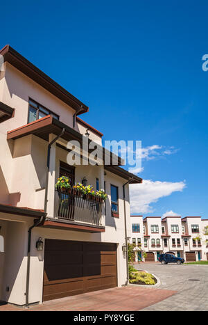 Maison d'habitation avec lit de fleur sur le balcon plus large porte de garage au niveau du sol. Maisons d'habitation sur fond de ciel bleu sur journée ensoleillée Banque D'Images