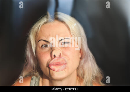 Visage de femme pressée contre le verre ou fenêtre, drôle expression visage féminin Banque D'Images