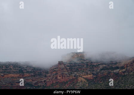 Le Colorado National Monument enveloppé d'une couche de brouillard. Les nuages au-dessus sont gris et sombre. Le ton général est abattu. Banque D'Images