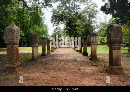 Allée pavée en pierre de latérite avec Free-standing stone posts aux portes de l'ancien temple Khmer Prasat Sdok Kok Thom dans Sa Kaeo province de Thaïlande Banque D'Images