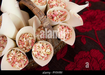 Un panier en osier marron naturel de pétale séché cônes confettis assis sur un canapé de couleur sombre Banque D'Images