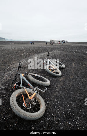 Tourisme à roues Fat des bicyclettes à l'épave de l'avion dans le désert de sable noir de Sólheimasandur ordinaire dans le sud de l'Islande. Banque D'Images