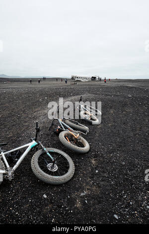 Tourisme à roues Fat des bicyclettes à l'épave de l'avion dans le désert de sable noir de Sólheimasandur ordinaire dans le sud de l'Islande. Banque D'Images