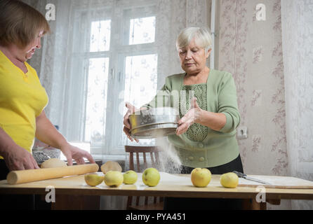 Deux personnes âgées femme faisant peu de tartes. La farine de tamisage Banque D'Images