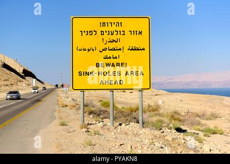 Un panneau de circulation avec un avertissement d'évier trous près des bords de la Mer Morte dans le désert du Néguev, près de En Guédi (Israël), le 27 septembre 2018. Dans le monde d'utilisation | Banque D'Images