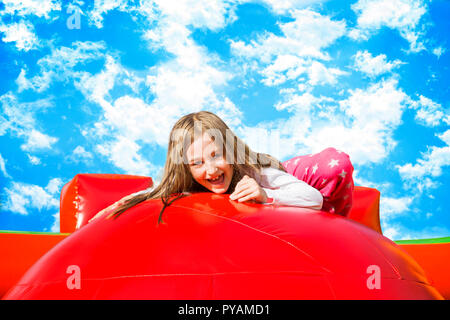 Happy little girl ayant beaucoup de plaisir sur un château gonflable tout en sautant sur les grosses boules. Banque D'Images