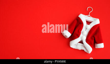 Fond de Noël Père Noël (Saint Nicolas) mini robe costume costume avec poignets blancs télévision restèrent isolées sur fond rouge. Photo Concept pour Merry Banque D'Images