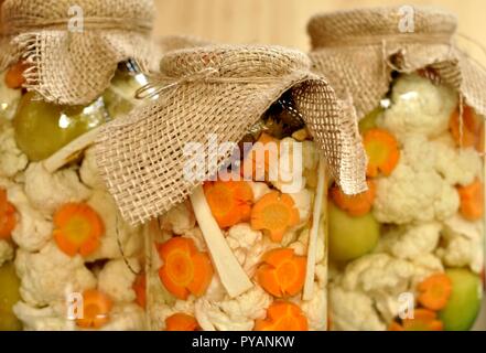 Concept de pot de cornichons de saison avec des tomates crues, de couleur verte, orange et Carotte Chou-fleur blanc sur fond de bois naturel. Vue avant Banque D'Images