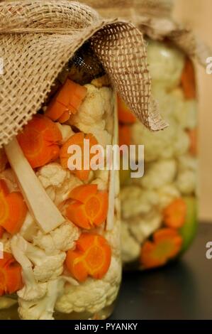 Concept de deux cornichons traditionnels de saison pot avec des tomates crues, de couleur verte, orange et Carotte Chou-fleur blanc sur fond de bois naturel. Banque D'Images