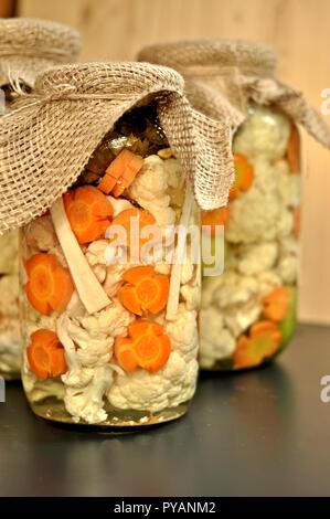 Concept de pot de cornichons de saison avec des tomates crues, de couleur verte, orange et Carotte Chou-fleur blanc sur fond de bois naturel. Vue avant Banque D'Images