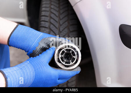 Automechanic, porter des gants de travail bleu, tenant un vieux joint homocinétique à l'avant du véhicule. Service de voiture, véhicule de remplacement des pièces. Banque D'Images