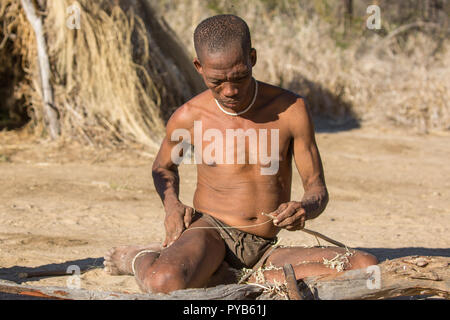 Un groupe de Bushmen la préparation des arcs et des flèches pour la chasse. Photographié en Namibie Banque D'Images