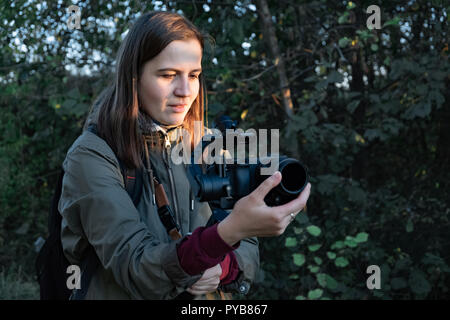 Femme tenant un vidéographe avec cardan mirrorless camera. Femme avec caméra stabilisée rig le tournage en extérieur sur un après-midi ensoleillé Banque D'Images