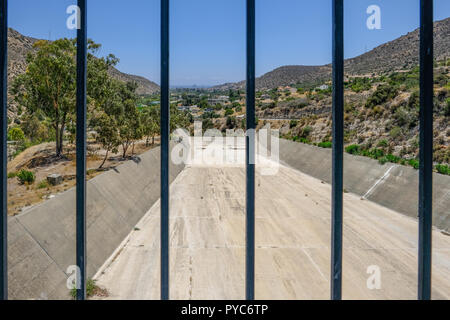 Débordement d'Germasogeia barrage sur un ciel bleu jour au début de l'été. Prise de vue en regardant à travers les garde-fous à l'écluse et sur la val Banque D'Images