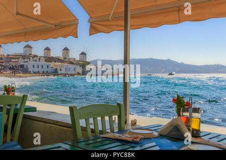 Mykonos, vue panoramique de célèbres moulins à vent blanc chaises avec tables de restaurant grec typique de la Petite Venise dans l'île des Cyclades, en Grèce. Banque D'Images