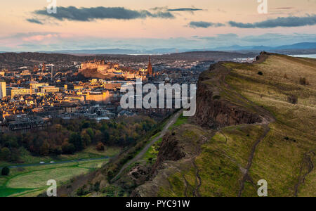 Vue de la Salisbury Crags de Arthur's Hill à Holyrood Park, à Édimbourg, avec le premier lever du soleil lumineuse éclairant le château en arrière-plan Banque D'Images