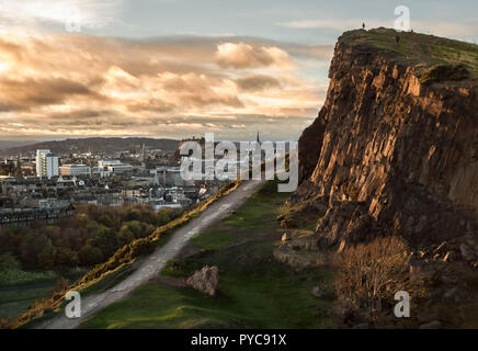 Vue de la Salisbury Crags à Holyrood Park, à Édimbourg, avec le Château en arrière-plan, et le soir la lumière sur la face de la falaise et les nuages Banque D'Images