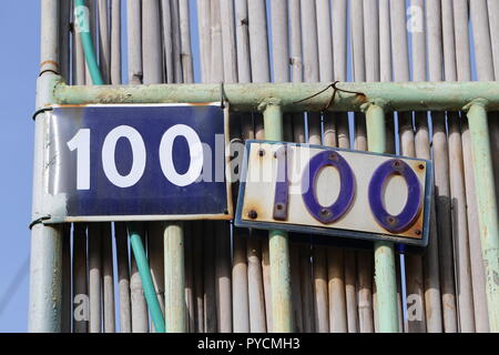 100 signe. Deux non. Lettres 100 sur les enseignes de maison. N° maison. 100 dans deux vieux panneaux de rue. Double nombre de cent signes de maison sur une clôture de maison en métal de fer. Banque D'Images