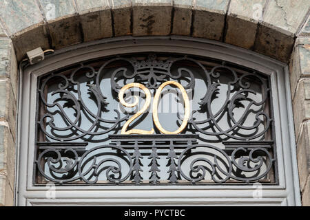 Numéro de maison vingt 20 en fer forgé design font notamment tourbillons et peint d'un jaune doré fixé sur base de métal noir inséré au-dessus d'une porte Banque D'Images