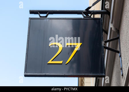 Numéro de maison vingt-sept 27 à découper le métal, designer font jaune doré peint sur fixe balck metal board suspendu à un bâtiment à partir de la Suède Banque D'Images
