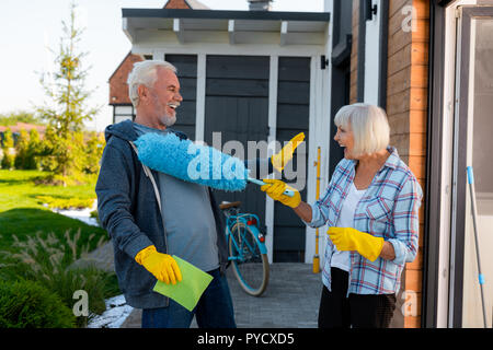 Couple de personnes âgées rire s'amuser tout en faisant le nettoyage près de summer house Banque D'Images