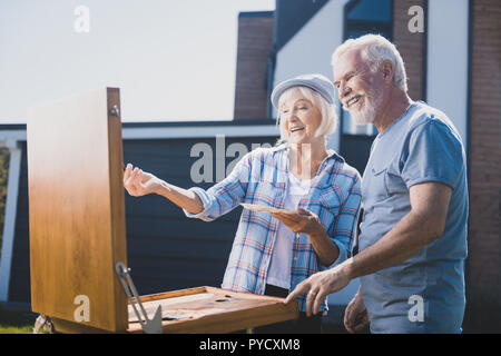 Couple de personnes âgées en riant tout en tirant toujours la vie dans leur ensemble de jardin Banque D'Images